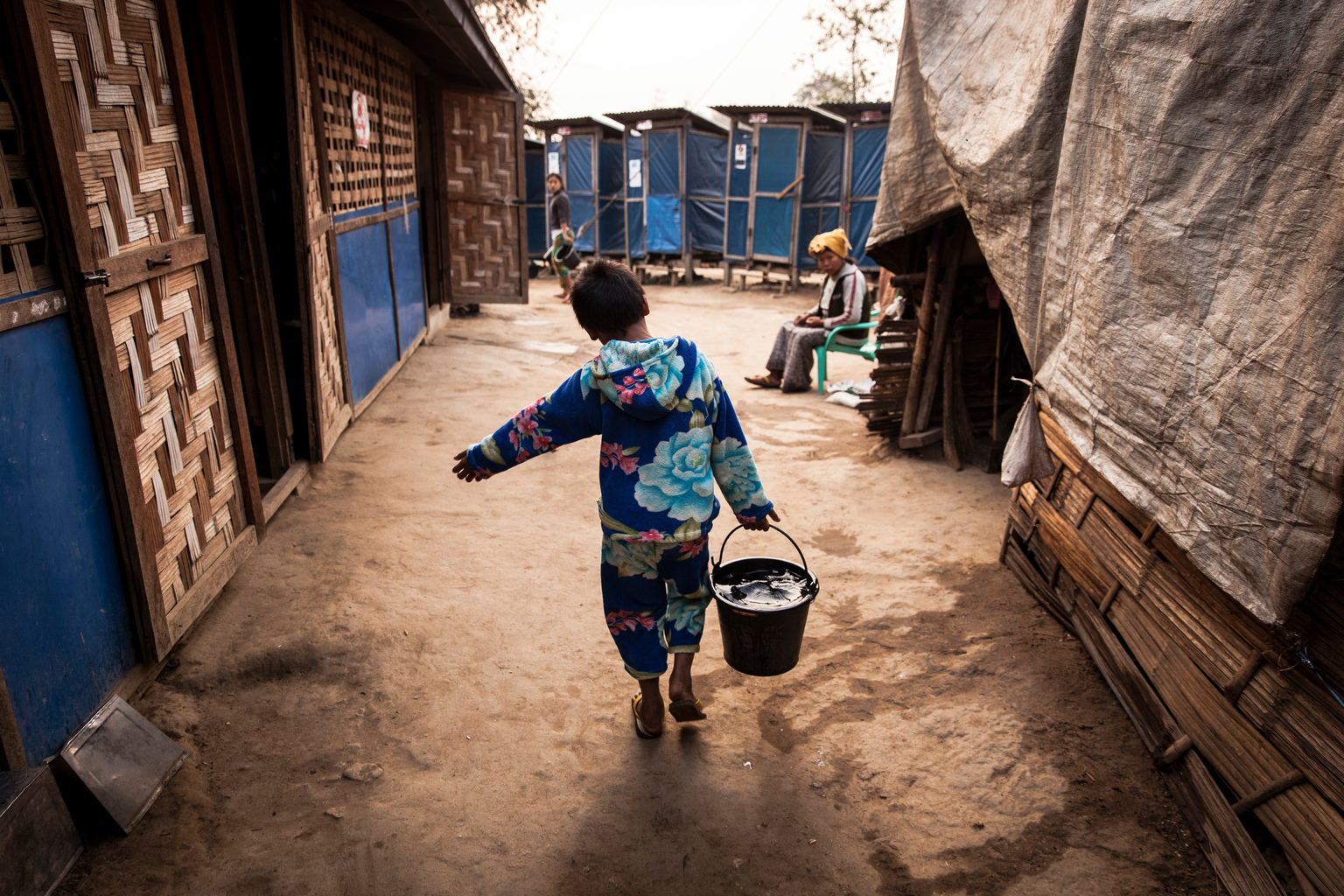 Aung Din, 12, displaced from Mung Ding Pa, collects water every morning for his household at the Phan Khar Kone IDP camp in Bhamo city, Kachin State, Myanmar, Wednesday 29 March 2017. Aung Din lives with his grandmother, mother and sister in the camp - his father was killed in a blast, most likely from a landmine while herding cattle, when fighting erupted between Kachin Independence Army (KIA) and the Myanmar Army in 2013. In 2017, working with the Government of Myanmar, UNICEF will strive to meet the basic needs of the most vulnerable internally displaced children. Myanmar is experiencing three protracted humanitarian crises, each with its own set of complex underlying factors. In Rakhine State, inter-communal violence that erupted in 2012 continues to plague 120,000 internally displaced people spread across 40 camps or informal sites, as well as host communities. Eighty per cent of the displaced are women and children. In Kachin State, armed conflict that reignited in 2011 continues to impact communities caught in the crossfire between an ethnic armed group and the Myanmar army. Nearly 87,000 people remain displaced as a result, including 40 per cent who are in areas outside of government control. An additional 11,000 people remain displaced in northern Shan State, where a similar conflict oke out in 2011. Compounding the protracted crises are issues related to religious and/or ethnic discrimination, exploitation, chronic poverty, vulnerability to natural disasters, statelessness, trafficking and humanitarian access. In addition to the humanitarian crises in Rakhine, Kachin and Shan states, Myanmar is impacted by humanitarian situations in other parts of the country, including natural disasters, health emergencies and small-scale displacements.