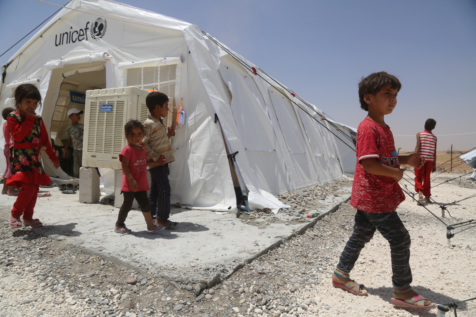 On 4 July 2017 in Ain Issa camp in the Syrian Arab Republic, displaced children from Raqqa leave a UNICEF child-friendly space which offers and a wide range of recreational activities. More than 6,600 people live in harsh desert conditions, as violence continues in the area. Since November 2016, unrelenting violence in the north eastern governorate of Raqqa has displaced over 200,000 people, almost half of whom are children. Intensified attacks have destroyed infrastructure and shattered civilian lives. Families are seeking safety in temporary shelters, with little access to basic services. In Ain Issa camp, UNICEF has set up six child-friendly spaces for learning and playing and is providing psychological support to more than 400 children to help them cope with the traumas they have faced and to regain a sense of structure and normality. In response to the needs of vulnerable families in the area, UNICEF is trucking in water daily to internally displaced people in camps in Raqqa and Hassakeh, including Maouka, Al-Hol and Ain Issa. UNICEF has installed latrines, showers and water storage tanks in the camps and is distributing family hygiene kits to protect children against waterborne diseases. Mobile health clinics have been set up to provide primary health care, including vaccinations for children and their mothers. Nutritional supplements are distributed on a regular basis.