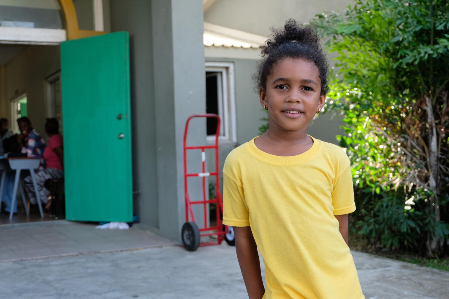 On 10 September, 6-year-old Bella Rian Jackson smiles outside the National Technical Training Centre in St. John's, capital of the island of Antigua. The education facility currently shelters displaced families from Barbuda whose homes were destroyed by Hurricane Irma. Bella, from Antigua, volunteers at the shelter with her grandparents, sorting and folding donated clothes, cleaning and tidying up the communal areas, and helping to distribute food and supplies. “I wanted to volunteer with my grandma,” Bella says. “If the children can’t come here, they’d [sic] have nowhere to go, and another storm could come,” she adds. More than 130 people, including scores of children, sheltered at the centre when the facility was at its busiest. On 6 September 2017, Hurricane Irma, the strongest hurricane ever recorded in the Atlantic, pummelled islands in the Eastern Caribbean. The category 5 storm left a path of destruction – especially on Anguilla, the British Virgin Islands, Barbuda and Turks and Caicos Islands. Some 73,000 people in this area, including 20,000 children, are affected, and at least 132 schools have been damaged. Irma disrupted communication networks in many areas and damaged or destroyed infrastructure, including roads, idges, hospitals and schools. The island of Barbuda suffered extensive damage during the disaster. Over 90 per cent of its buildings were destroyed, with homes, schools, the island’s only hospital, and other infrastructure destroyed or severely damaged. A 2-year-old boy was also killed during the storm, and most of Barbuda’s nearly 2,000 residents have been displaced. Officials quickly evacuated the vast majority of the population to Antigua, Barbuda’s sister island, ahead of an anticipated category four hurricane (Hurricane Jose) expected to wreak additional destruction on the already devastated island. Antiguans have rallied to support their compatriots, with church and community groups volunteering at shelters hosting