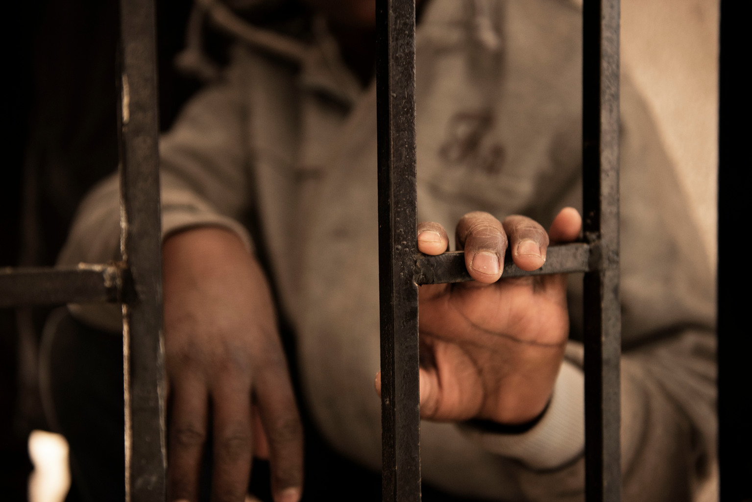 Fourteen-year-old Issaa, a migrant from Niger, rests his hand on a gate inside a detention centre, in Libya, Saturday 28 January 2017. Issaa, who has five younger others, said his mother died two years ago in Niger. I left Niger two and a half years ago, he says sitting on one of the dozens of dirty mattresses on the floor. My father collected money for my journey, he wished me good luck and then let me go. Once I arrived in Libya I started to look for a job.