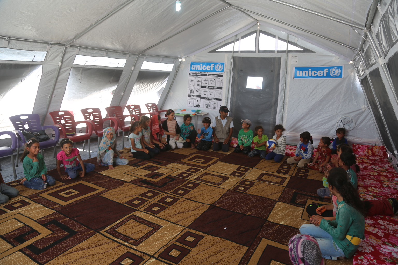 On 4 July 2017 in Ain Issa camp in the Syrian Arab Republic, displaced children from Raqqa attend a UNICEF psychosocial support programme. More than 6,600 people live in harsh desert conditions, as violence continues in the area. Since November 2016, unrelenting violence in the north eastern governorate of Raqqa has displaced over 200,000 people, almost half of whom are children. Intensified attacks have destroyed infrastructure and shattered civilian lives. Families are seeking safety in temporary shelters, with little access to basic services. In Ain Issa camp, UNICEF has set up six child-friendly spaces for learning and playing and is providing psychological support to more than 400 children to help them cope with the traumas they have faced and to regain a sense of structure and normality. In response to the needs of vulnerable families in the area, UNICEF is trucking in water daily to internally displaced people in camps in Raqqa and Hassakeh, including Maouka, Al-Hol and Ain Issa. UNICEF has installed latrines, showers and water storage tanks in the camps and is distributing family hygiene kits to protect children against waterborne diseases. Mobile health clinics have been set up to provide primary health care, including vaccinations for children and their mothers. Nutritional supplements are distributed on a regular basis.